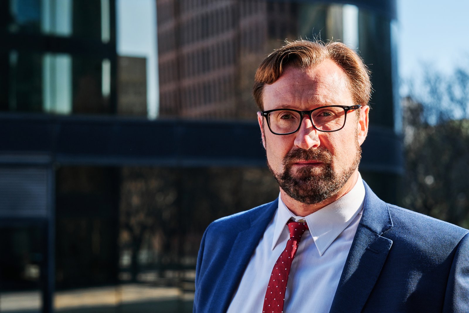 Close up portrait of a serious caucasian adult businessman with eyeglasses in the city street